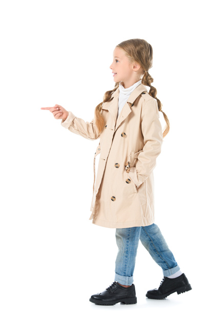criança adorável em casaco bege apontando em algum lugar, isolado em branco
  - Foto, Imagem