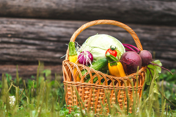 Fresh vegetables in basket on grass on wooden background. - Fotografie, Obrázek