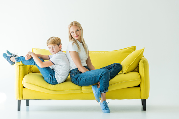 mère et fils assis dos à dos sur canapé jaune sur blanc
 - Photo, image