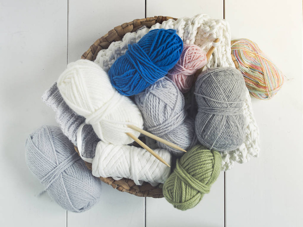 Different kinds of colorful wool in wicker basket on white floor - Fotó, kép