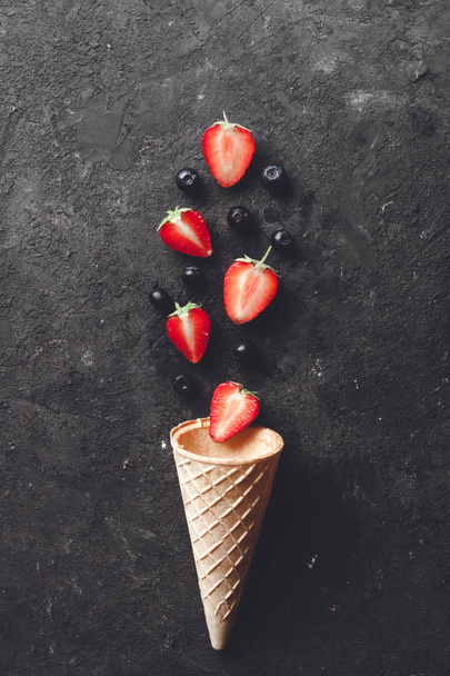 Crispy waffle cone with blueberries and strawberries on black background with copy space. - Φωτογραφία, εικόνα