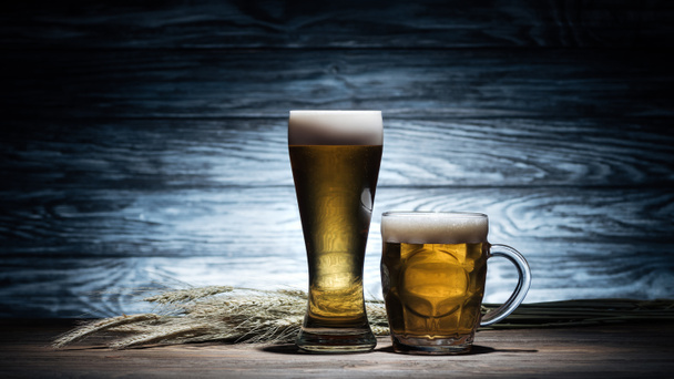 two glasses of golden beer and wheat spikelets on wooden table, oktoberfest concept - Photo, Image