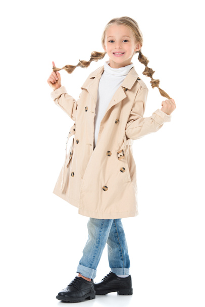 adorable blonde kid with braids posing in beige coat, isolated on white - Photo, Image