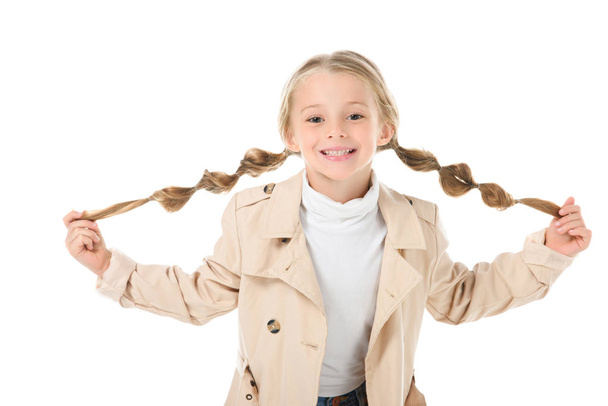 happy child with braids posing in beige coat, isolated on white - Zdjęcie, obraz
