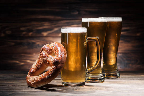 glasses of beer and tasty pretzel on wooden surface, oktoberfest concept - Photo, image