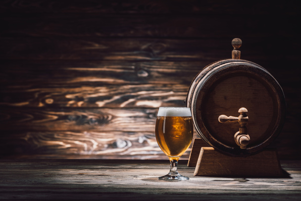 glass of tasty beer and beer barrel on wooden table, oktoberfest concept - Photo, Image