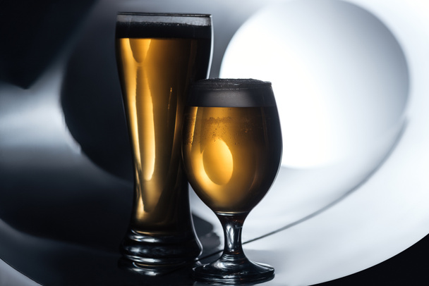 bier in de glazen op witte en zwarte achtergrond, oktoberfest concept - Foto, afbeelding