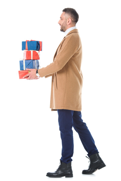 handsome man in beige coat holding gift boxes, isolated on white - Photo, image