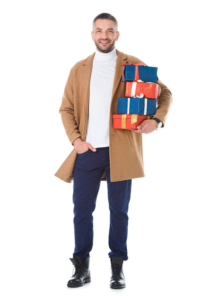 handsome man in stylish beige coat holding gift boxes, isolated on white - Фото, изображение