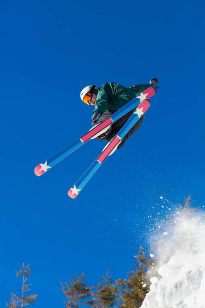 Niski kąt strzału narciarz extreme freeride, skoki w powietrzu na nartach w górach ciesząc się słoneczny zimowy dzień Sport Rekreacja styl życia emocje wolności młodzieży hobby. - Zdjęcie, obraz