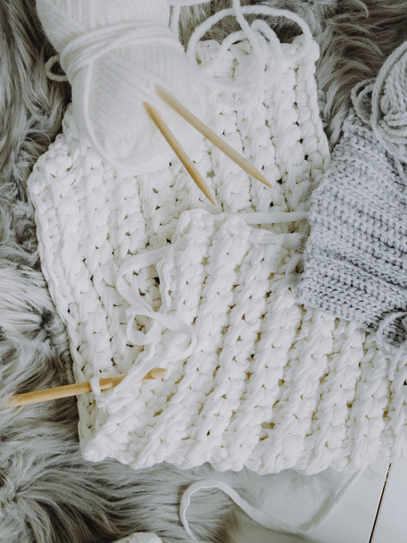 Cozy composition of white and gray wool with crochet hook and knitting needles - Фото, изображение