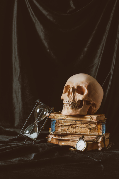 halloween skull on ancient books with sand clock on black cloth - Photo, Image
