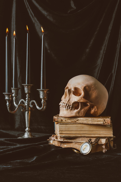 black halloween candles, skull and ancient books on black cloth - 写真・画像