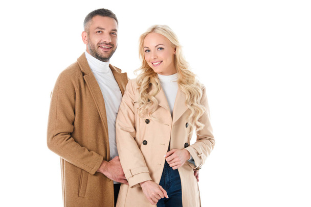 όμορφο ζευγάρι χαμογελώντας θέτοντας σε μπεζ παλτό, απομονώνονται σε λευκό - Φωτογραφία, εικόνα