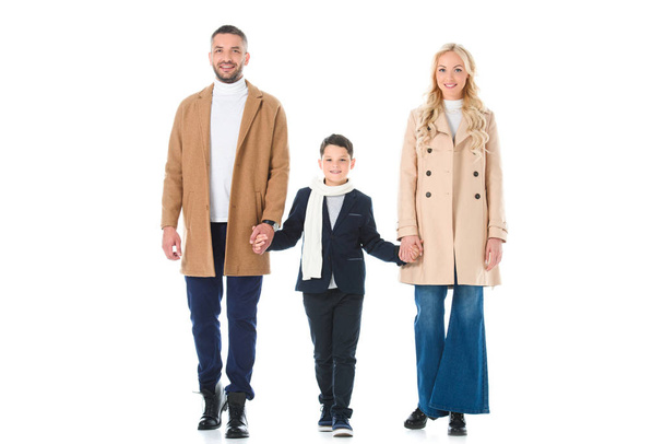 Οι γονείς σε μπεζ παλτό και γιος κρατώντας τα χέρια, απομονώνονται σε λευκό - Φωτογραφία, εικόνα