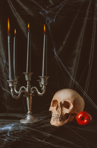 skull, red apple and candelabrum with candles on black cloth with spider web - Foto, Bild