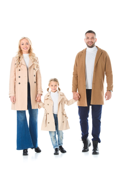 happy parents holding hands with adorable daughter and posing in beige coats, isolated on white - Photo, Image