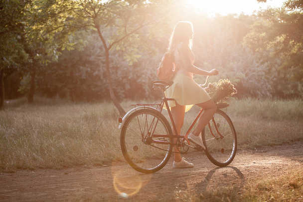 Beautiful sports girl on a retro bike in the park for a walk. - 写真・画像