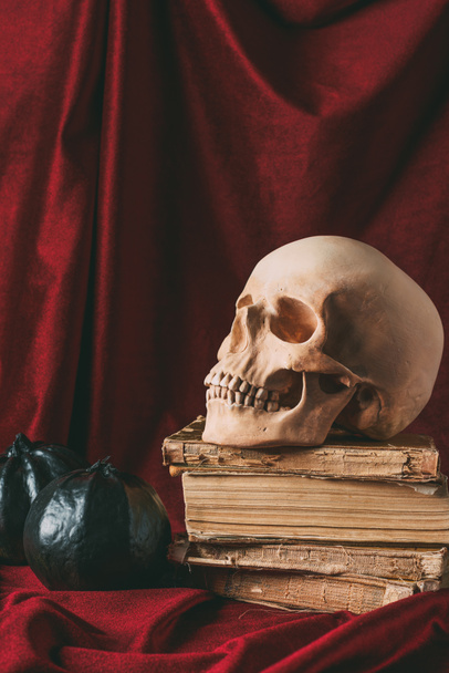 halloween skull on ancient books with black pumpkins on red cloth - Фото, изображение