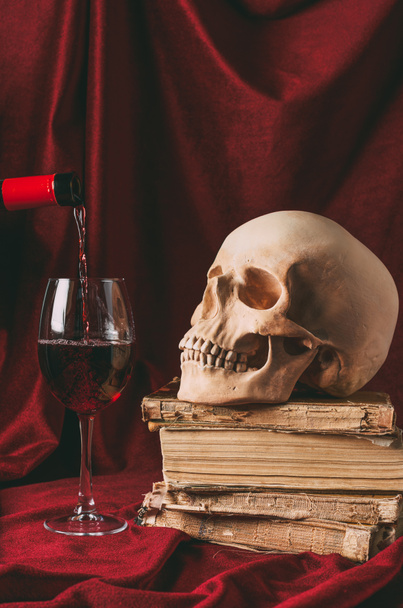 vinho tinto, crânio de Halloween em livros antigos sobre pano vermelho
 - Foto, Imagem