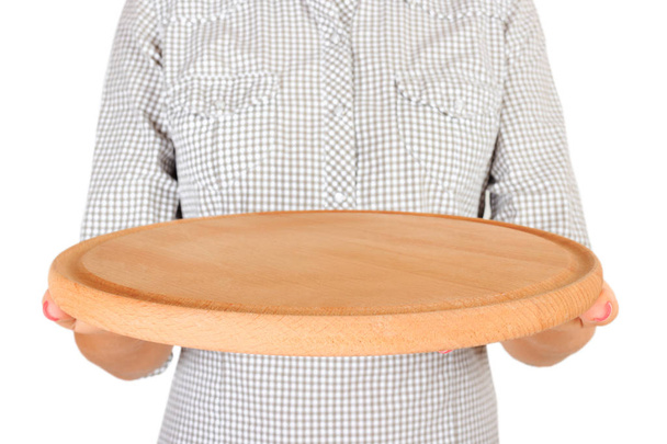 chica en la camisa a cuadros está sosteniendo un plato redondo vacío de madera para pizza en frente de ella. la mano de la mujer sostiene el plato vacío para usted que diseña. vista de perspectiva, aislado sobre fondo blanco
. - Foto, Imagen