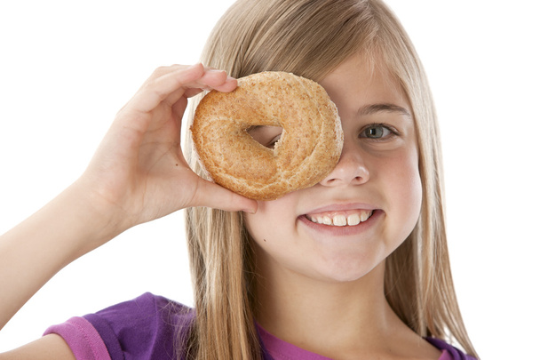 Healthy Eating. Caucasian little girl peeking through the hole of a bagel - Foto, Imagen