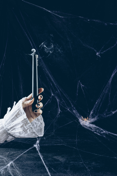 cropped view of mystic woman holding smoky candle in darkness with spider web - Foto, afbeelding