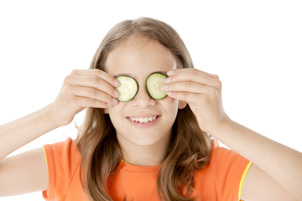 Healthy Eating. Caucasian little girl holds cucumber slices over her eyes - Фото, изображение