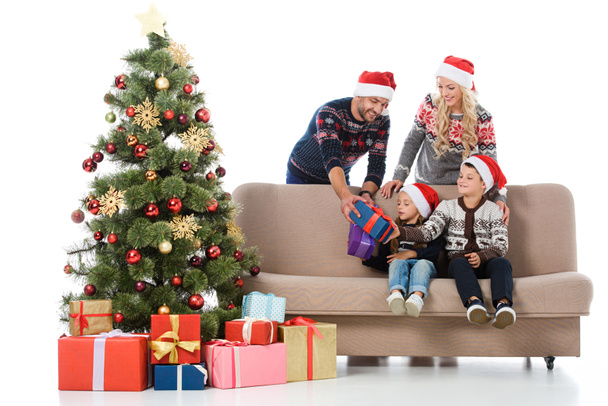 parents dans des chapeaux de Père Noël donnant des cadeaux aux enfants assis près de l'arbre de Noël, isolé sur blanc
 - Photo, image