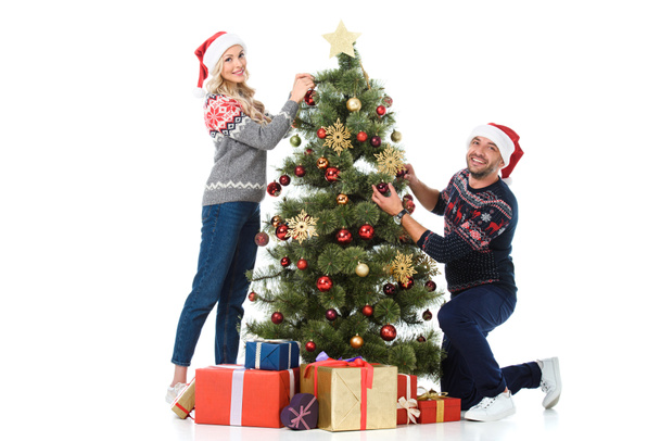 feliz pareja decorando árbol de Navidad con cajas de regalo, aislado en blanco
 - Foto, Imagen