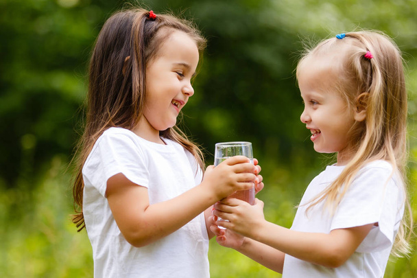 Due bambine che bevono un bicchiere d'acqua a Green Park. Concetto di purezza, prodotto ecologico e biologico, amore per la natura
 - Foto, immagini