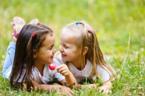 Due bambine che si rilassano e mangiano un lecca-lecca in un parco
 - Foto, immagini