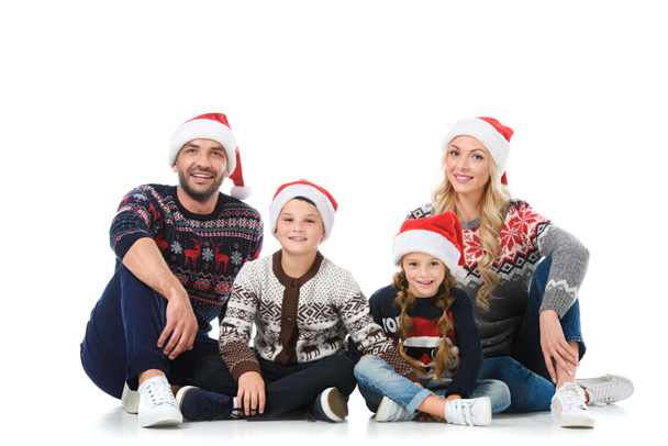 happy parents with children sitting in christmas sweaters and santa hats, isolated on white - Foto, Imagem
