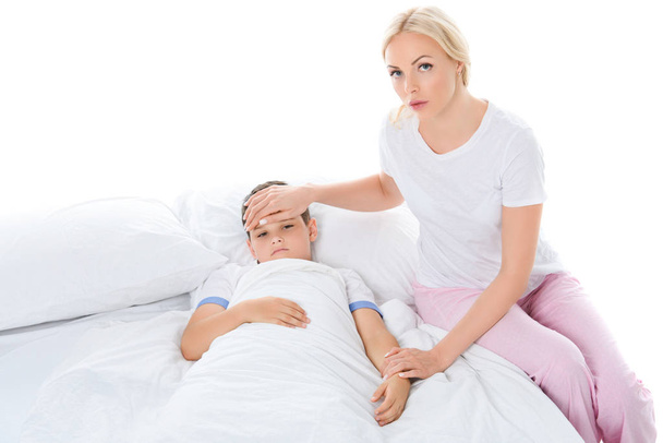mother touching forehead of sick son with temperature, isolated on white - Foto, imagen
