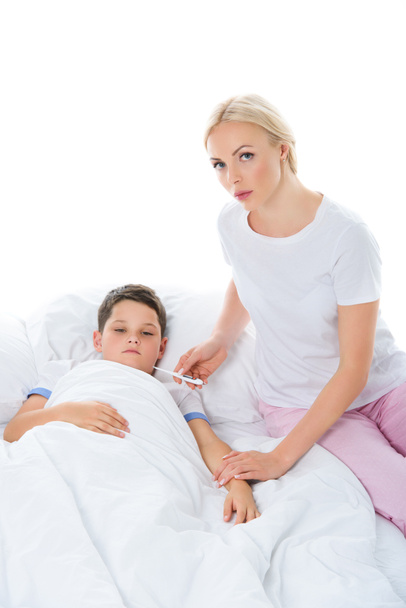 mother with electronic thermometer sitting near sick son, isolated on white - Fotoğraf, Görsel