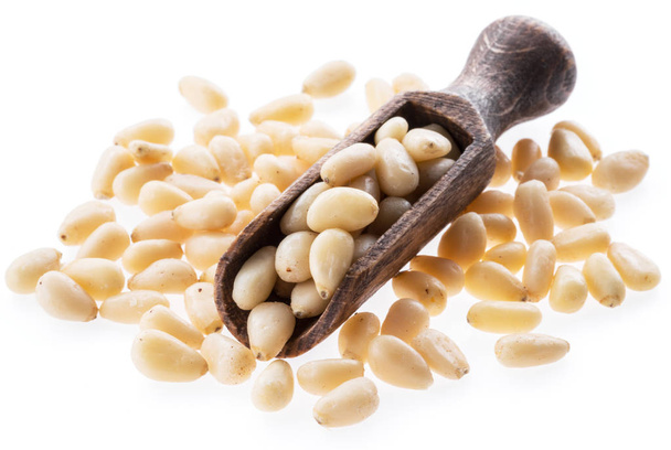 Pine nuts in the wooden scoop. White background. - 写真・画像