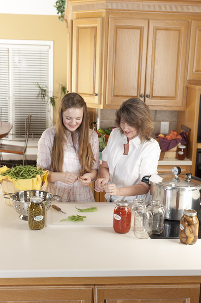 Canning. Mãe branca e filha adolescente enlatando legumes caseiros
 - Foto, Imagem