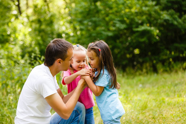 Pai brincando com suas filhas no parque verde
 - Foto, Imagem