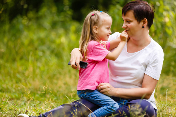 cute brunette female with daughter outdoor in spring time, smiling faces, happiness and love concept - Valokuva, kuva