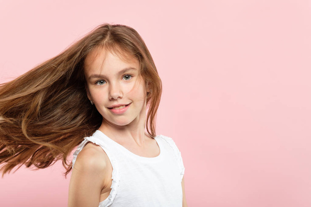 haircare and styling for kids. beauty and health. quality shampoo and conditioner products or hair salon for children. adolescent girl with wavy locks flying in the wind on pink background. - 写真・画像
