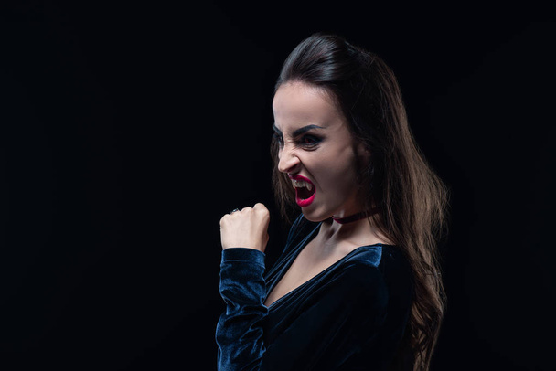 schreckliche Frau zeigt Vampirzähne isoliert auf schwarz - Foto, Bild