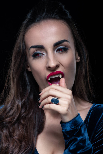 sexy vampier aanraken haar fang geïsoleerd op zwart - Foto, afbeelding