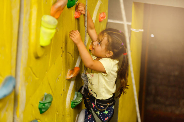 little girl climbing a rock wall indoor - Photo, Image