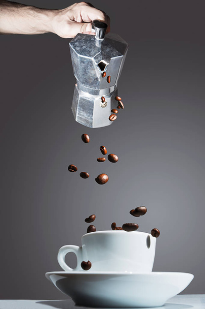 Cafetière versant des grains de café torréfiés dans la tasse
 - Photo, image