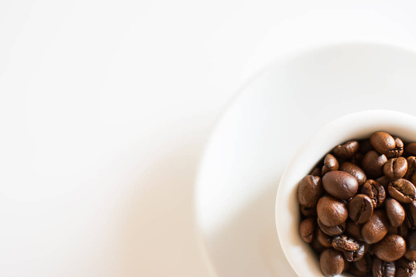 Kaffeetasse voller gerösteter Kaffeebohnen und weißem Hintergrund - Foto, Bild