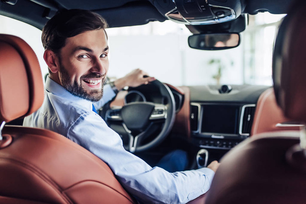 portrait of young smiling businessman sitting in the car and looking at the camera - Foto, immagini