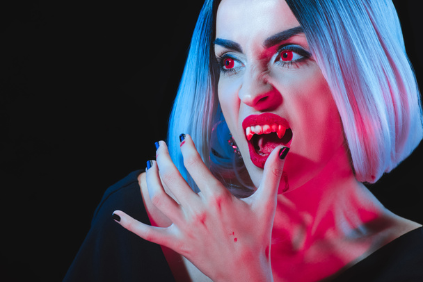 grim vampire licking her fingers isolated on black - Фото, зображення