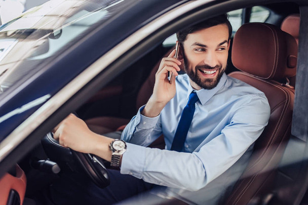 portrait of caucasian bearded businessman talking on cellphone while sitting in the car - Foto, imagen
