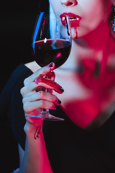 cropped view of vampire drinking blood from wineglass isolated on black - Фото, зображення