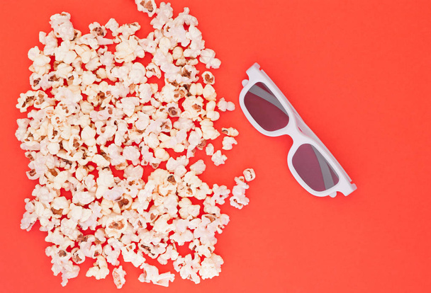 White 3d glasses and fresh cheesy popcorn on a red background, top view, copyspace. Cinema Concept. - 写真・画像
